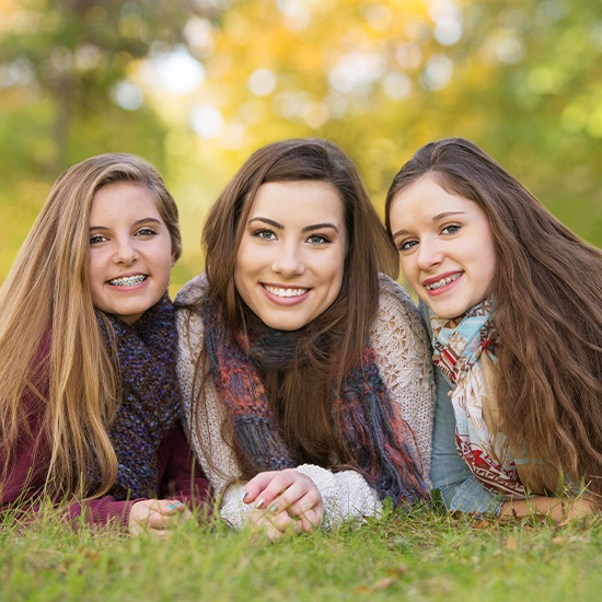 Three teen girs with healthy smiles two with traditional braces