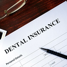 Dental insurance paperwork on desk with glasses and X-ray