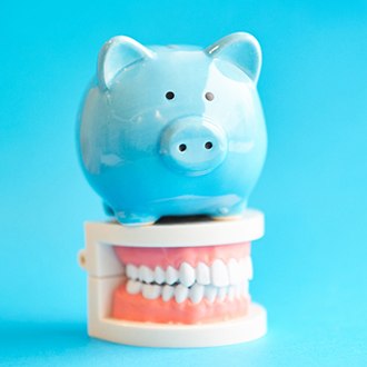 Piggy bank and teeth representing cost of orthodontic emergencies in Marlborough