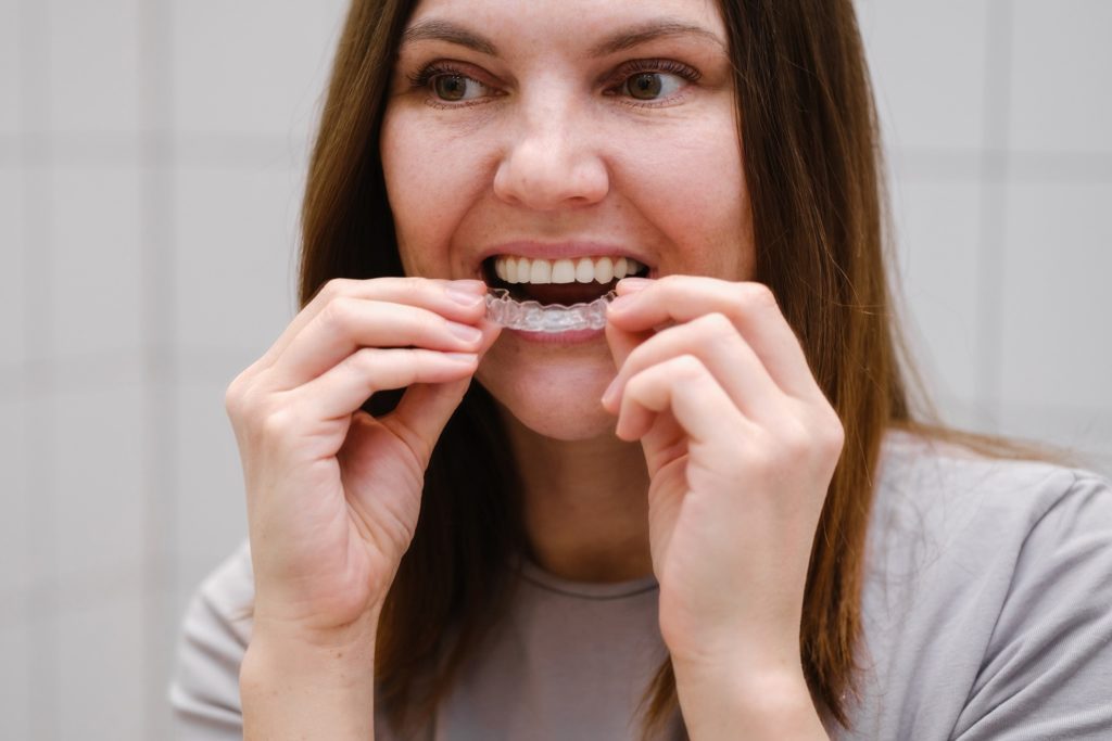 Woman looking in mirror while removing clear aligners