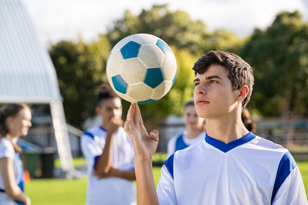 Teen boy spinning soccer ball on finger